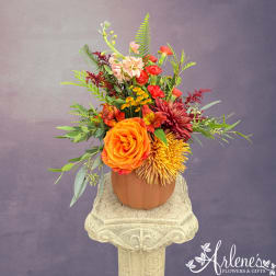 Mixed orange, red, and yellow flowers arranged in a pumpkin-shaped vase