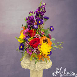 Colorful flower arrangement with roses, chrysanthemums, and a pumpkin accent in a pedestal vase