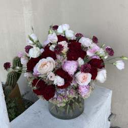 Bouquet of red and blush roses with pale lisianthus in a glass vase