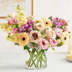 Mixed pastel flowers arranged in a clear glass vase