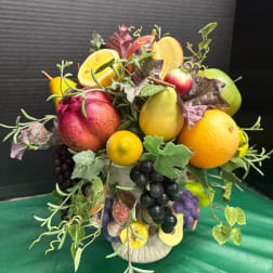 Fruit arrangement with faux citrus, pears, grapes, and leaves in a vase