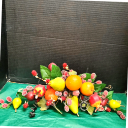 Fruit arrangement with pears, oranges, apples, and berries on a green surface