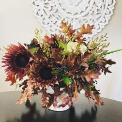 Autumn bouquet with dark sunflowers in a white vase