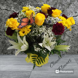 Bouquet of yellow roses, white lilies, and burgundy flowers in a vase