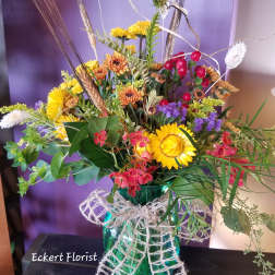 Mixed bouquet in a teal glass vase with yellow and orange flowers