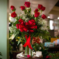 Red roses in a glass vase with a red ribbon bow