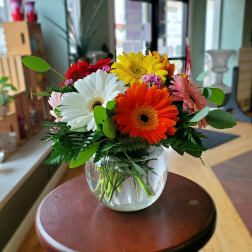 Colorful gerbera daisy bouquet in a round glass vase