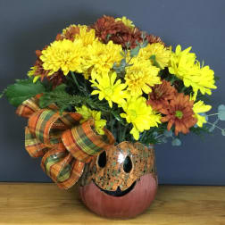 Yellow and rust chrysanthemum arrangement in a pumpkin vase with plaid ribbon