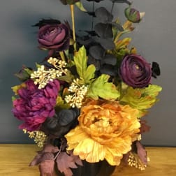 Purple and yellow artificial flowers in a black vase