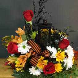 Floral arrangement with red roses, lilies, daisies, and a black lantern