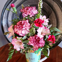 Pink and white flower arrangement in a decorative mug