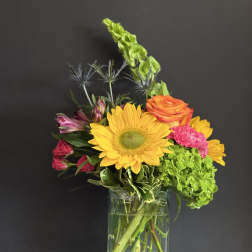 Mixed bouquet with a sunflower, roses, hydrangea, and alstroemeria in a glass vase