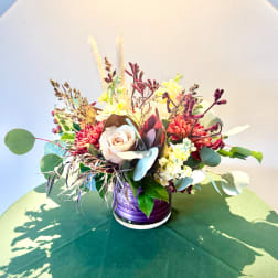 Mixed floral arrangement in a purple vase with cream and red blooms