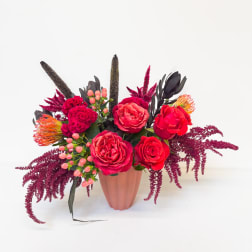 Bright red floral arrangement in a pink vase
