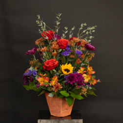 Mixed bouquet in a terracotta vase with red roses and colorful daisies