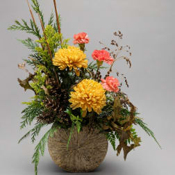 Yellow chrysanthemums and pink carnations in a rustic vase arrangement
