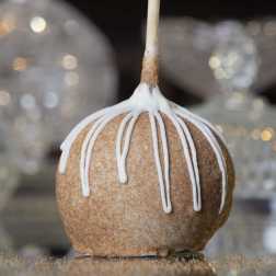 Caramel apple with white icing drizzle on a stick