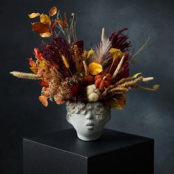 Autumn floral arrangement in a sculpted face vase