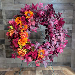 Circular wreath with orange and magenta flowers on a metal stand