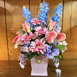 Pink and blue artificial flower arrangement in a pink vase