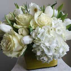 White roses and hydrangeas arranged in a yellow vase