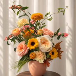 Mixed bouquet in a peach vase with pink, yellow, and cream flowers