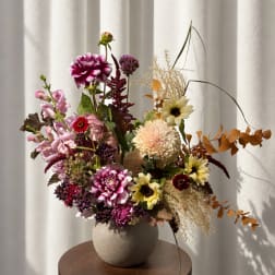 Mixed floral arrangement in a round vase with pink, cream, and burgundy blooms