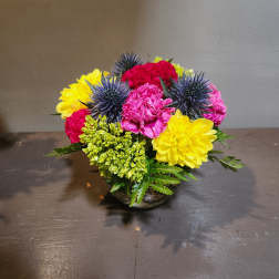 Colorful mixed flower arrangement in a low glass bowl