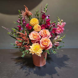 Mixed bouquet with peach roses, yellow dahlias, and magenta snapdragons in a pink vase