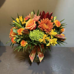 Mixed orange and yellow bouquet in a glass vase with a plaid ribbon