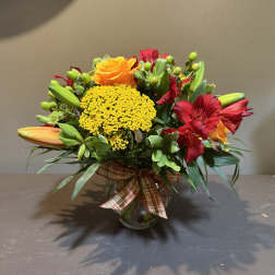 Mixed bouquet in a glass vase with orange roses and red lilies