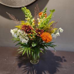 Mixed bouquet in a clear glass vase with orange, white, and yellow blooms