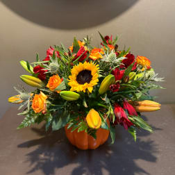 Sunflower and lily arrangement in a small orange pumpkin vase
