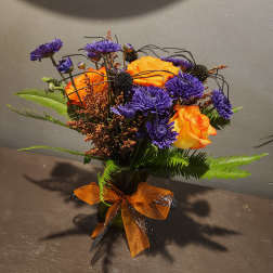 Orange roses and purple mums in a vase with an orange ribbon