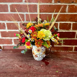 Mixed fall bouquet in a floral mug vase with daisies and mums