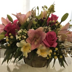 Pink lilies and roses in a basket arrangement