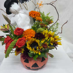 Halloween floral arrangement in a painted pumpkin container with a stuffed ghost