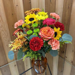 Mixed bouquet of bright flowers in an amber glass vase