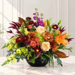 Mixed bouquet in a black bowl vase with orange lilies and purple blooms