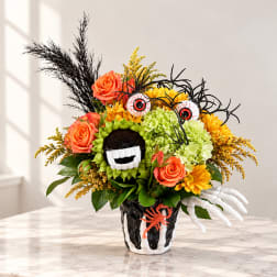 Halloween bouquet with orange roses, yellow flowers, and spooky decorations in a black vase