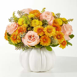 Peach roses and yellow-orange mums in a white pumpkin vase