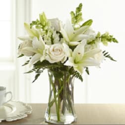White lilies and roses arranged in a clear glass vase