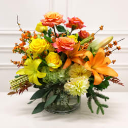 Bright mixed bouquet in a clear glass vase with roses and lilies