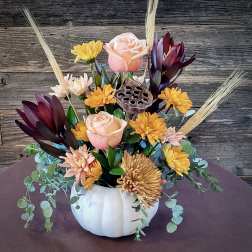 Autumn floral arrangement in a white pumpkin vase with roses and mums
