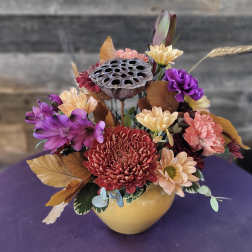 Mixed chrysanthemum arrangement in a yellow vase with dried lotus pod