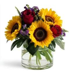 Sunflowers and red roses arranged in a clear glass vase