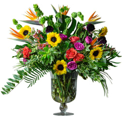 Mixed bouquet with sunflowers, roses, and tropical flowers in a glass vase