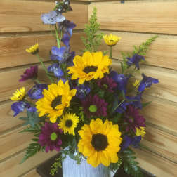 Bouquet of yellow sunflowers and purple daisies in a white vase