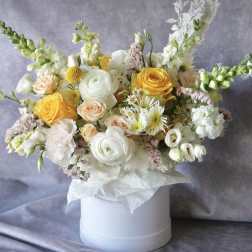 Mixed bouquet of yellow and white flowers in a white hat box