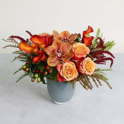 Orange calla lilies and peach roses in a light blue vase